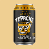 A 12 fl oz can of Tepache Spiced Pineapple soda on a solid beige background. The can features a black label with a yellow skull wearing sunglasses, and the brand name 'TEPACHE' in white.
