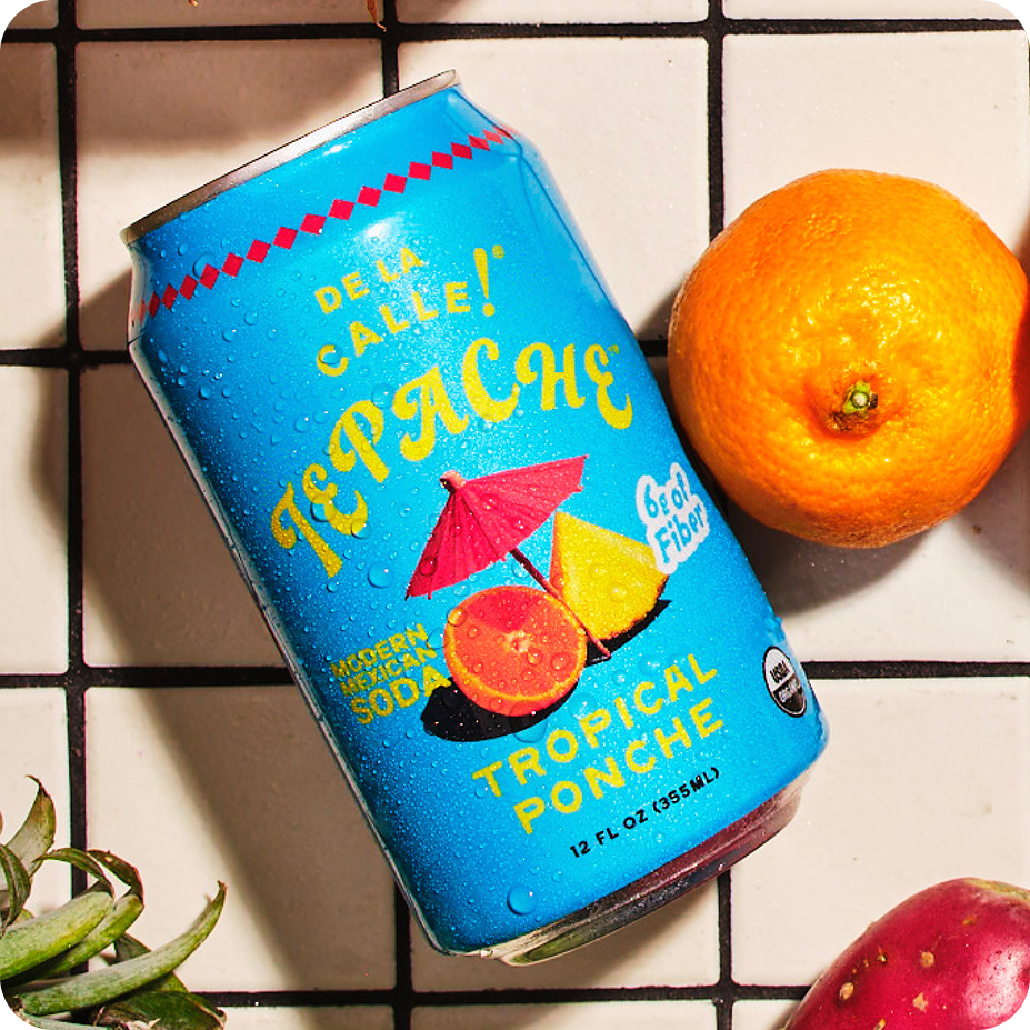 Can of Tepache tropical ponche with an orange on a tiled surface