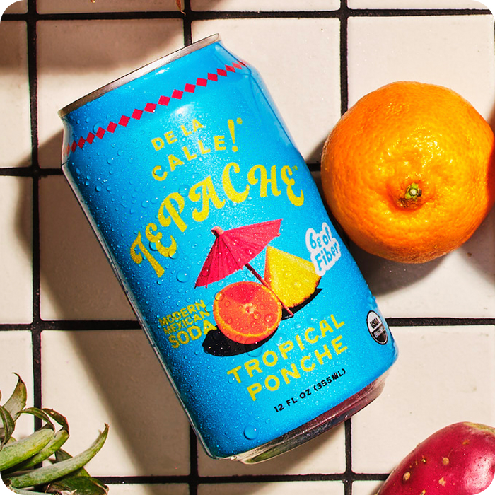 Can of Tepache tropical ponche with an orange on a tiled surface